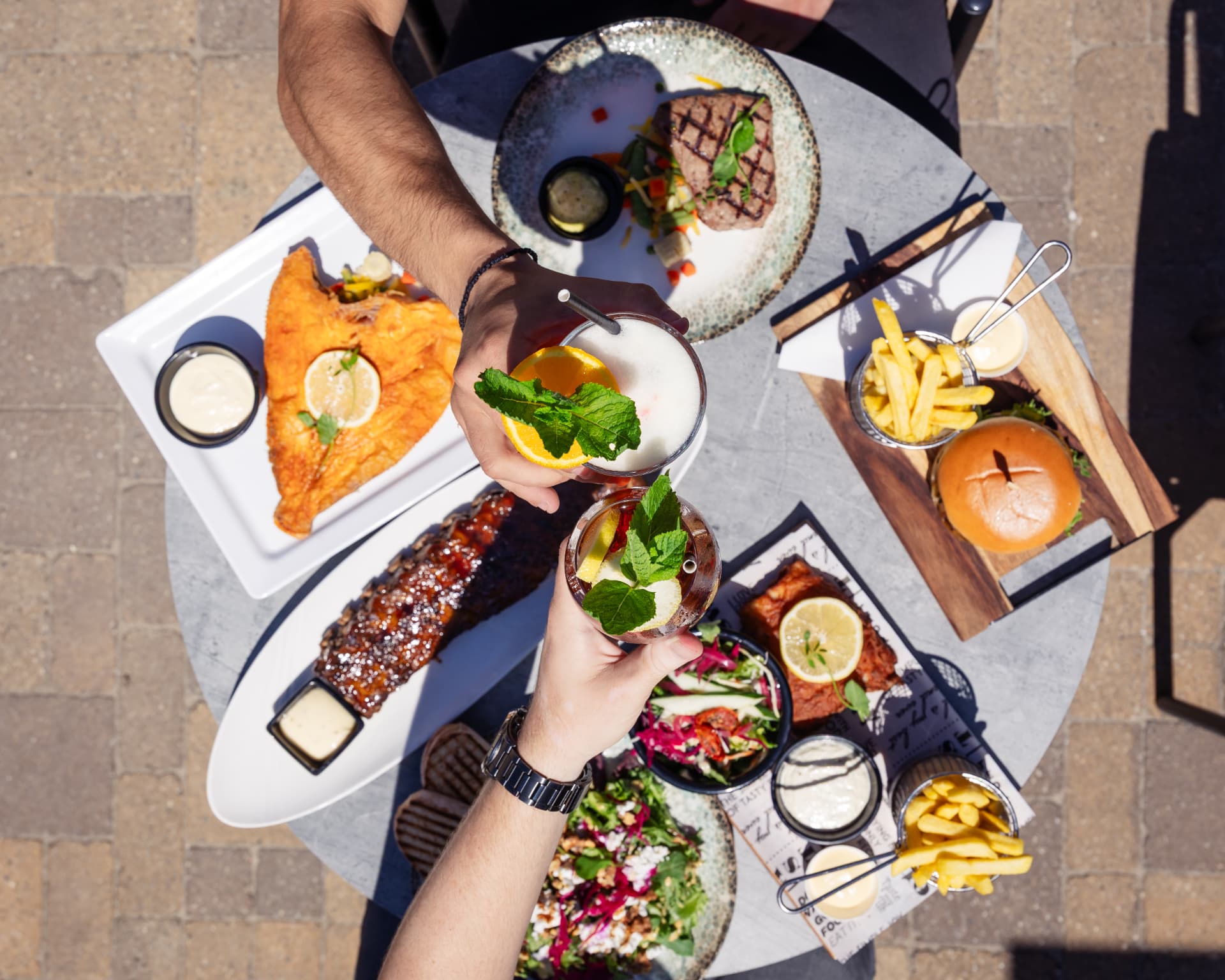 Table full of dishes and cocktails on the terrace of Paal 28